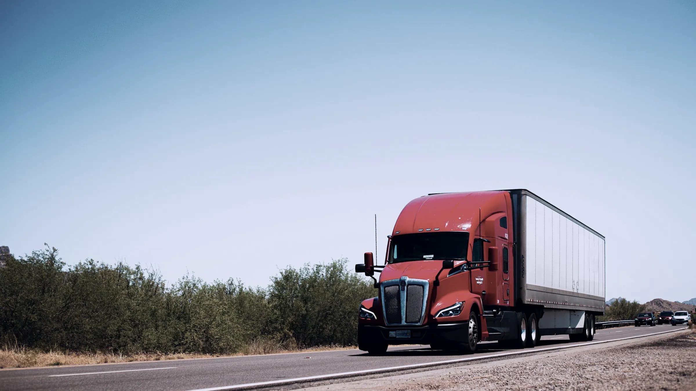 A tractor-trailer on the road under a clear sky